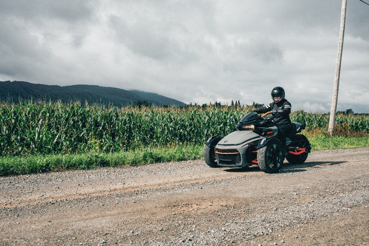 CAN-AM SPYDER ON GRAVEL ROAD, WITH CORN FIELD IN BACKROUND. 